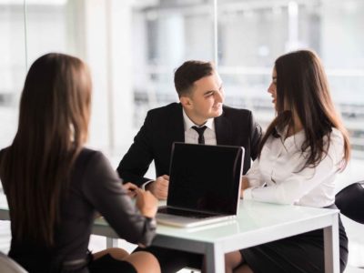 contract-with-best-conditions-confident-young-woman-explain-some-details-document-pointing-it-with-smile-while-sitting-together-with-young-couple-desk-office